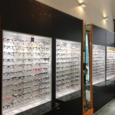 Diverse étagères de lunettes affichées dans un magasin optique bien éclairé.
