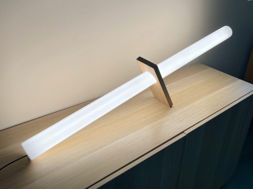 Lampe moderne en forme de sabre, avec un tube lumineux et une base en bois.