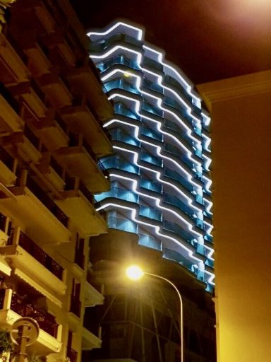 Bâtiment moderne illuminé la nuit avec des lignes lumineuses.