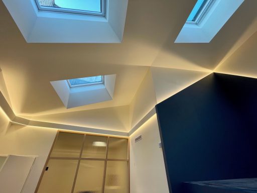 Plafond moderne avec fenêtres de toit et éclairage LED indirect.