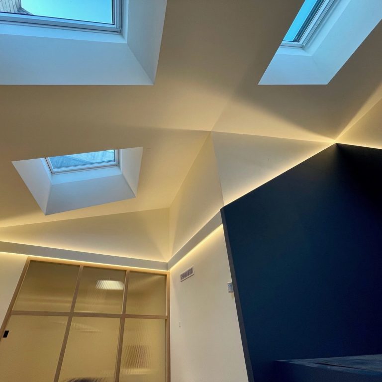 Plafond moderne avec fenêtres de toit et éclairage LED blanc chaud en corniches, murs wall en bleu foncé.