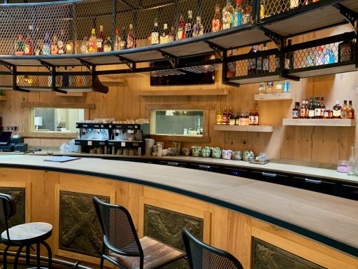 Bar élégant avec étagères de bouteilles, sièges confortables et ambiance chaleureuse.
